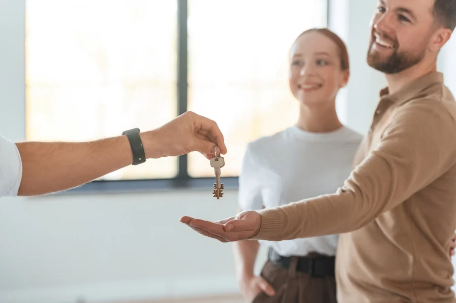 Schlüsselübergabe an neue Mieter in einer hellen Wohnung